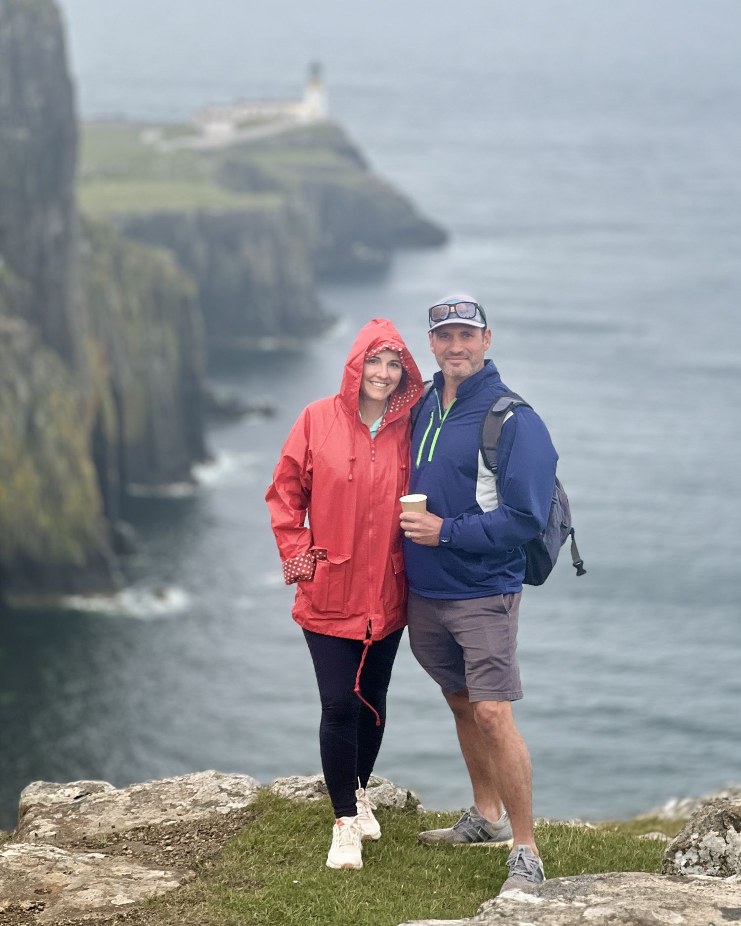 couple on cliffs with Neist Point Lighthouse Isle of Skye