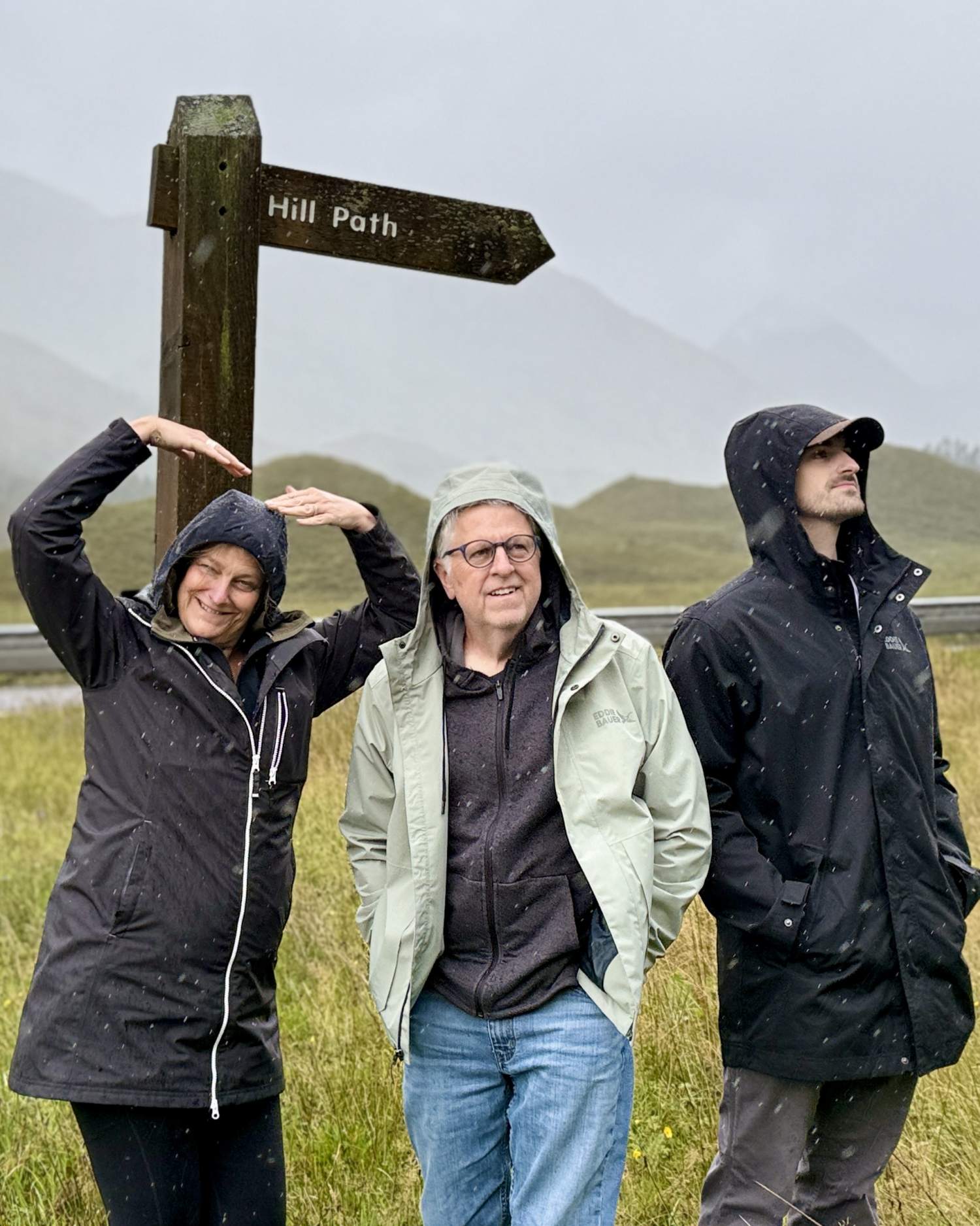 family enjoying rainy moment under Highland trail sign